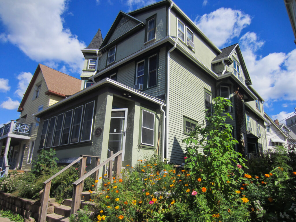 Green house surrounded by flowering plants.